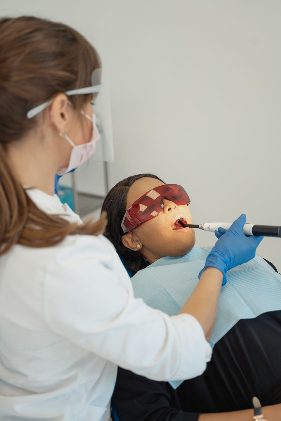 Dentist gently treating a patient wearing protective glasses
